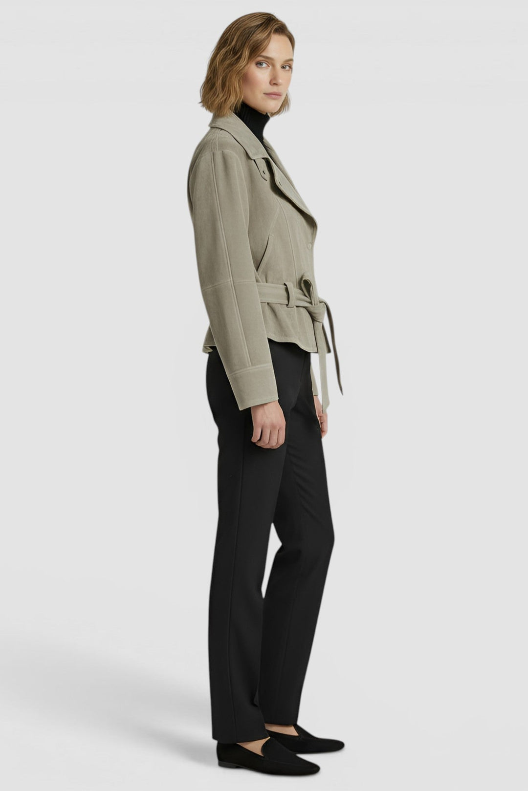 ADELINE - Side profile of model in greenish-tan suede jacket and black trousers