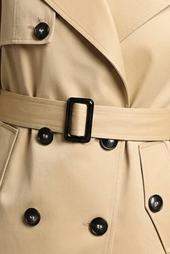 ALVERA - Woman wearing a beige trench coat against a gray background