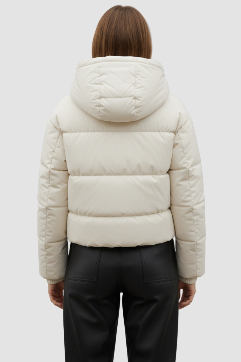 A person dressed in a white puffer jacket stands against a gray background.