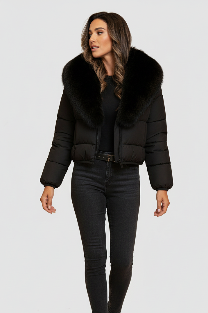 A woman dressed in a black puffer jacket with a fur collar stands against a plain white background.