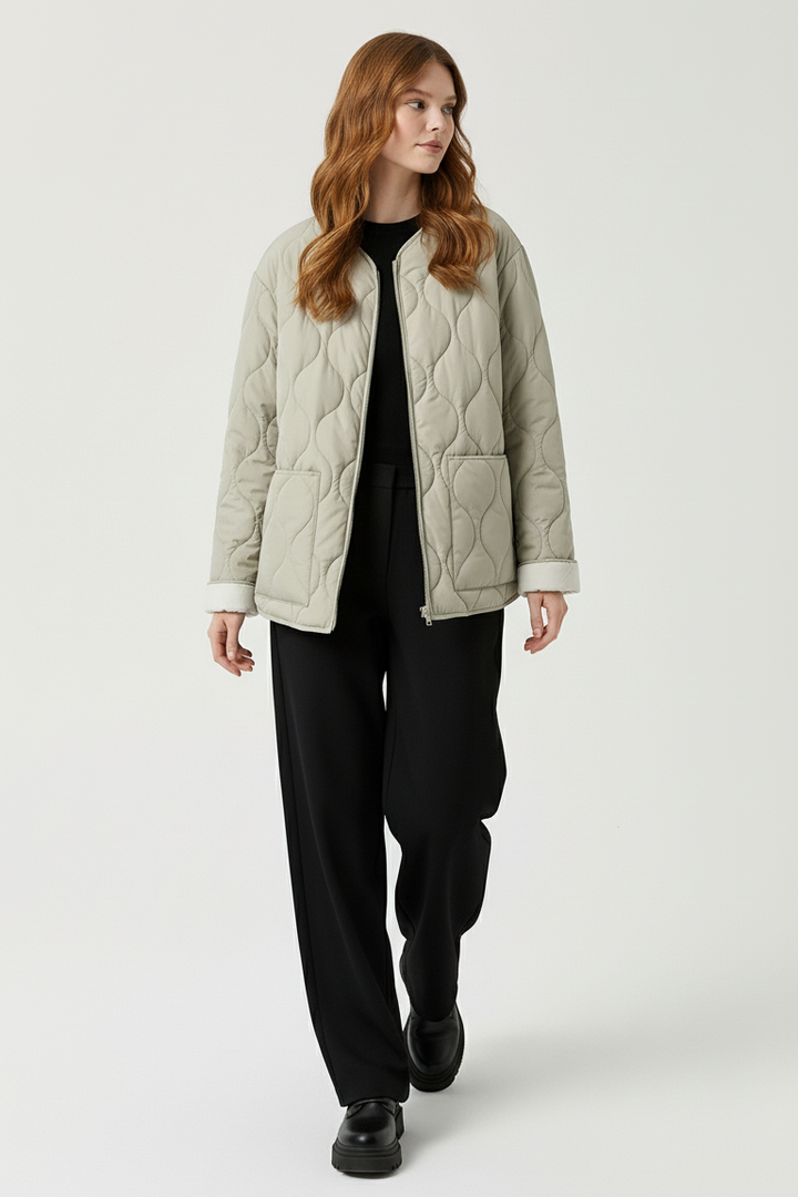 A woman dressed in a light green quilted jacket against a plain white background.