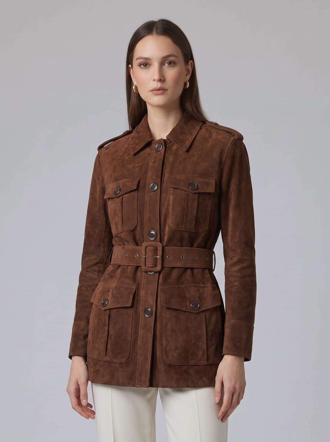 A woman modeling a brown suede utility jacket with a matching belt, shown against a plain light gray studio background.