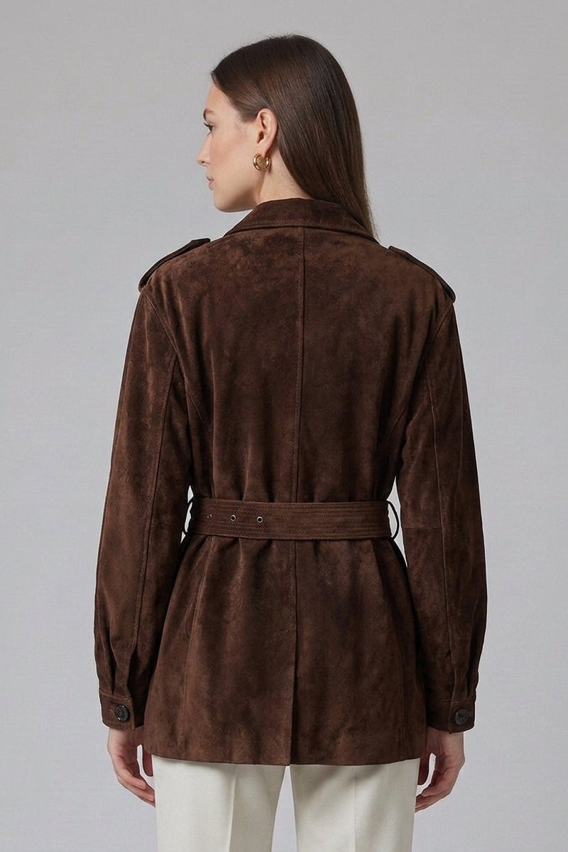 A woman shown from the back wearing a dark brown suede belted jacket and cream trousers, photographed against a neutral gray studio background.