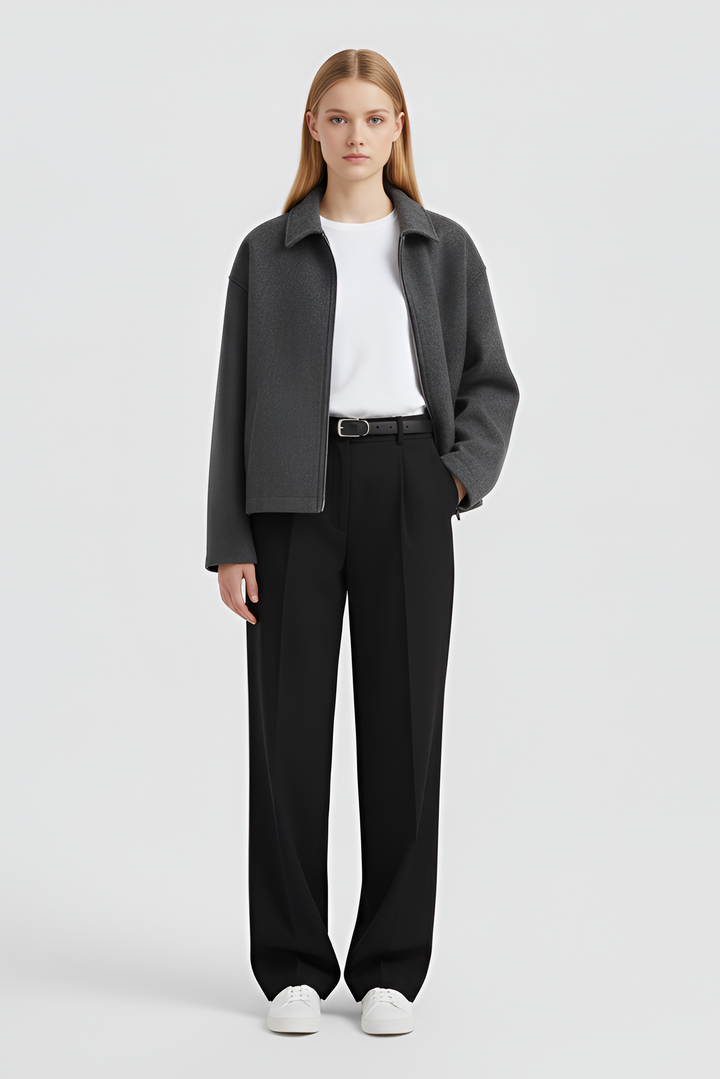 Woman wearing a gray coat, white shirt, black pants, and white shoes on a light gray background