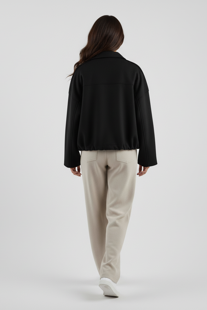 Person wearing a black jacket and beige pants on a white background