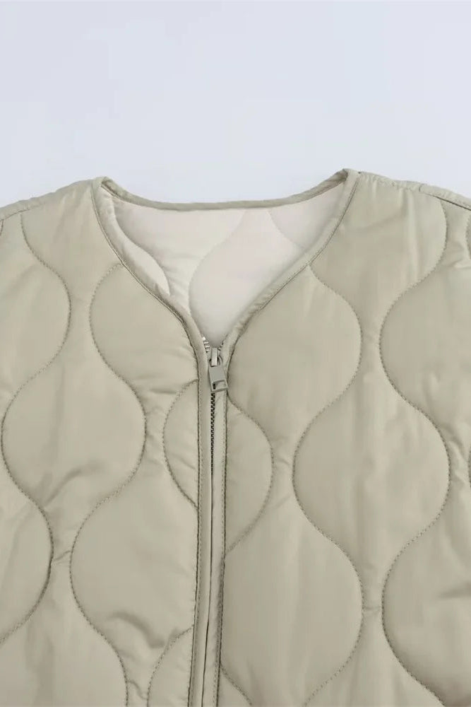 Beige quilted vest with a zipper on a light gray background