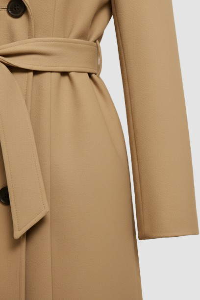 Close-up of a beige trench coat with a belt on a light gray background