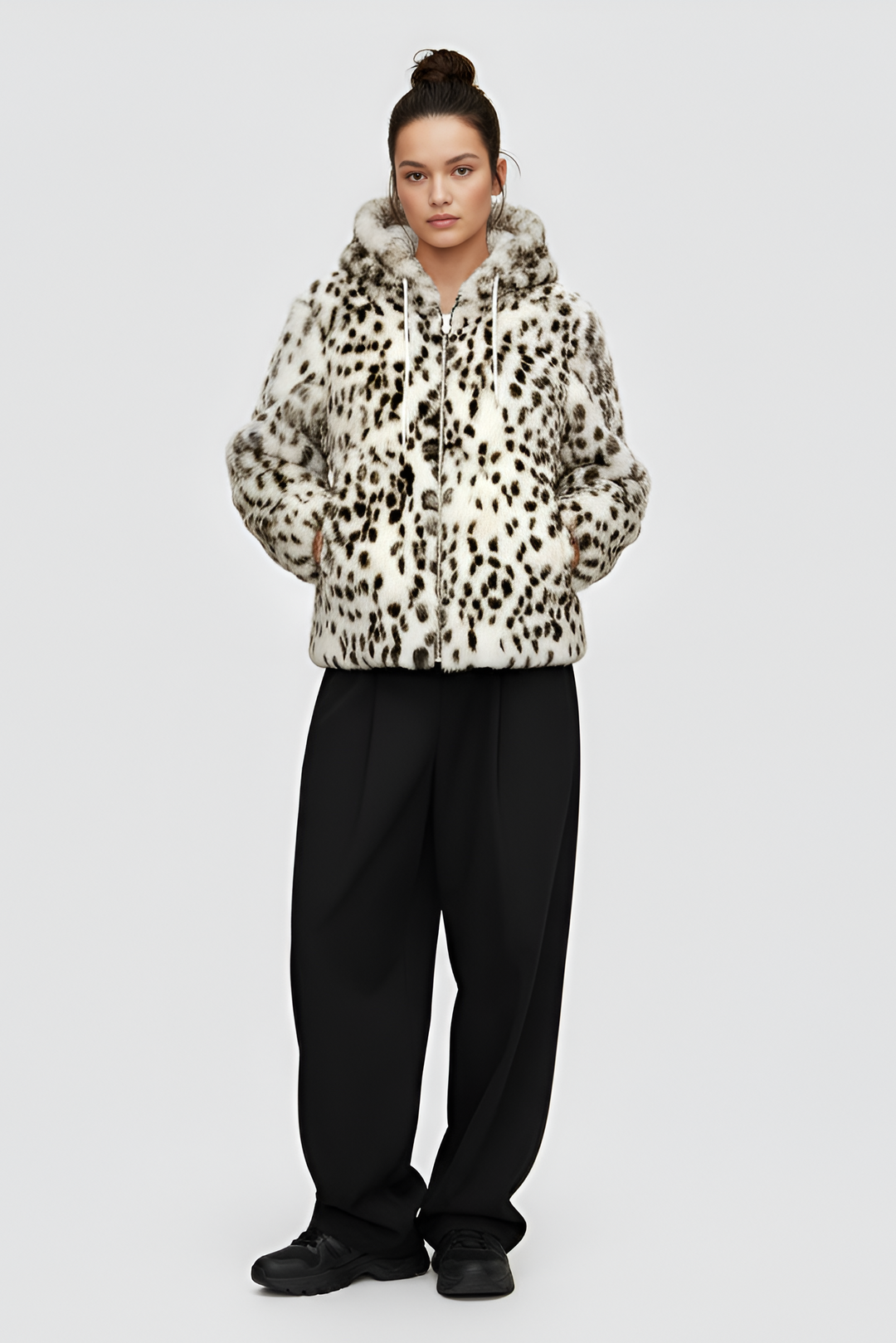 Woman wearing a patterned jacket over a black top and pants on a gray background