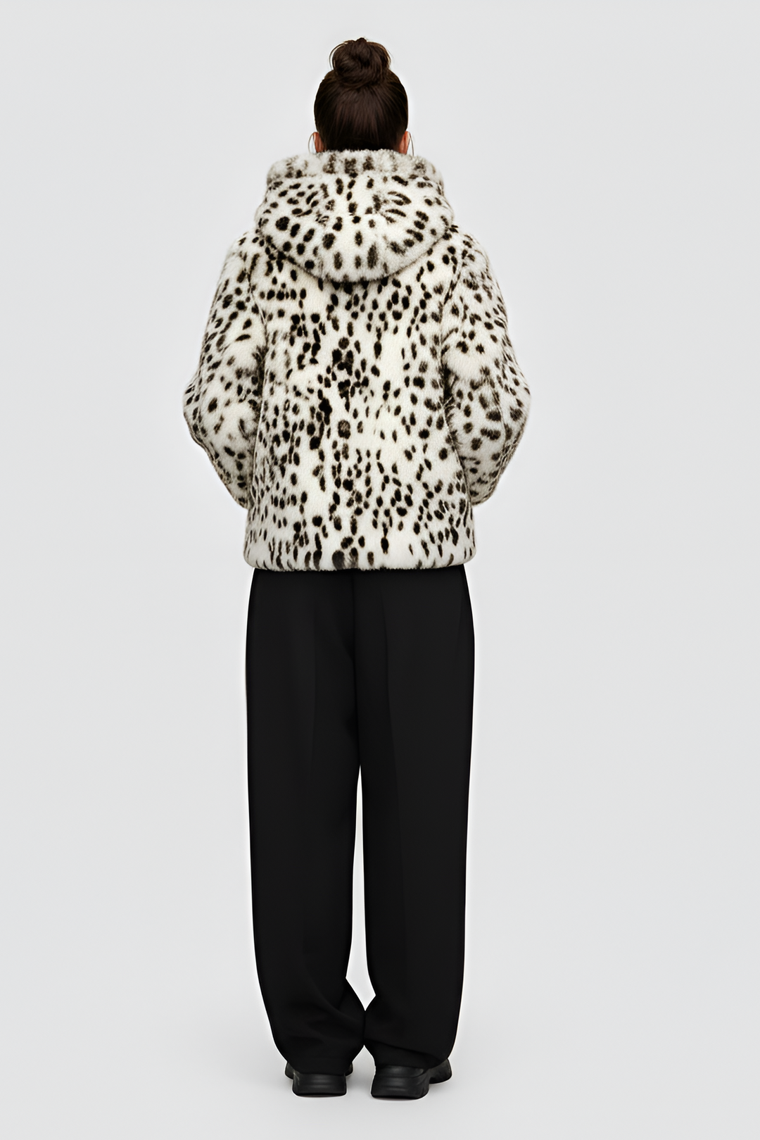 Woman wearing a patterned jacket over a black top and pants on a gray background