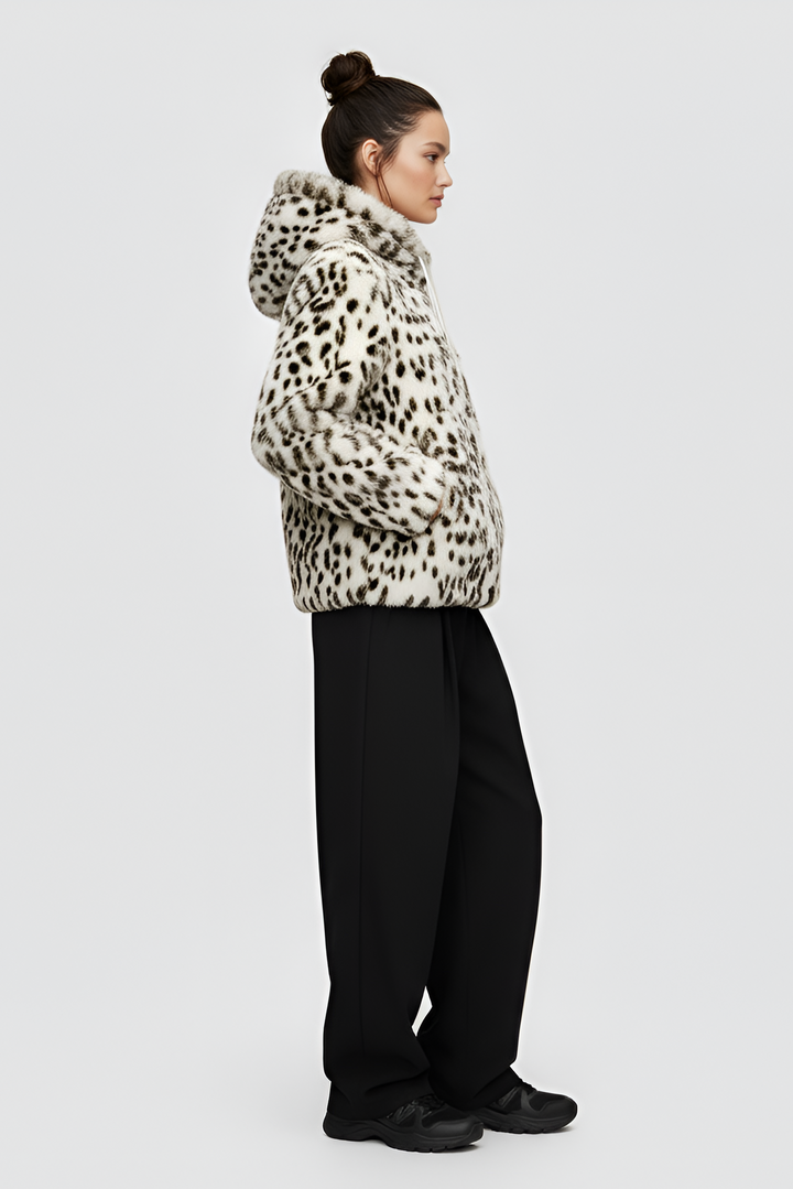 Woman wearing a patterned jacket over a black top and pants on a gray background