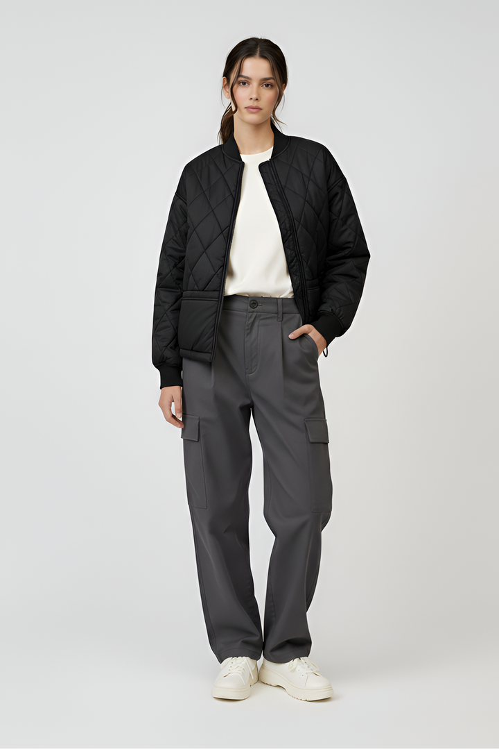 Person wearing a black jacket, white shirt, gray pants, and white sneakers on a light gray background