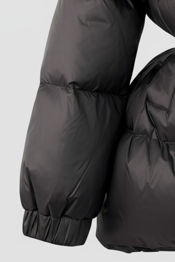 Black puffer coat with fur trim on a light gray background