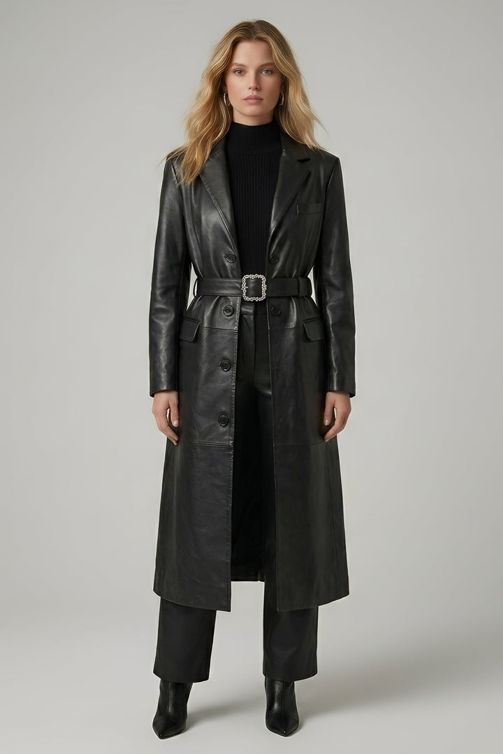 Woman wearing a long black leather coat on a plain background