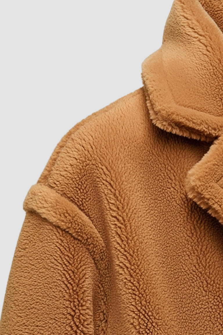 Close-up of a brown fleece jacket with a hood on a white background