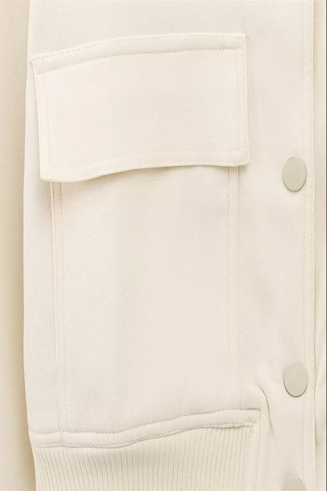 Close-up of a cream-colored cardigan with buttons on a white background