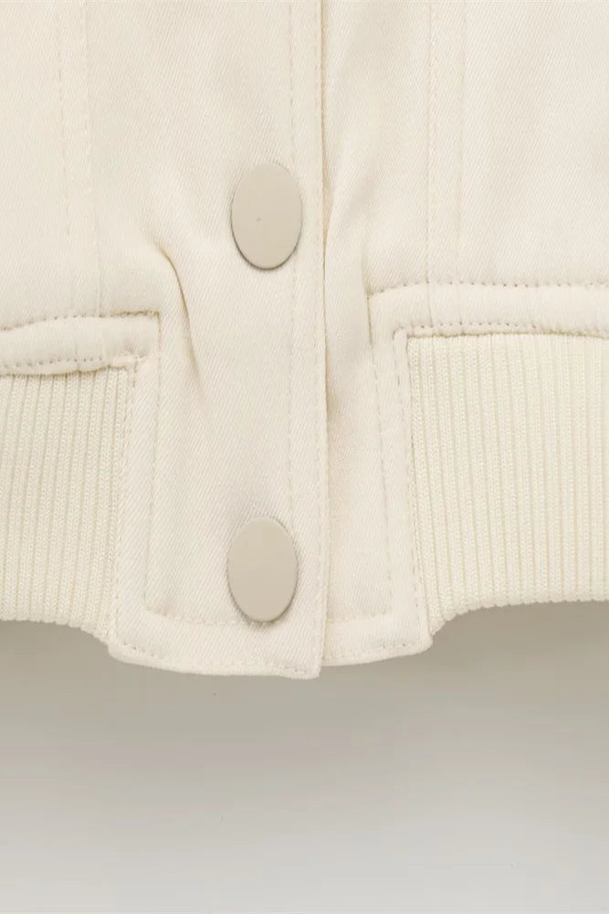 Close-up of a cream-colored jacket with button details on a light gray background
