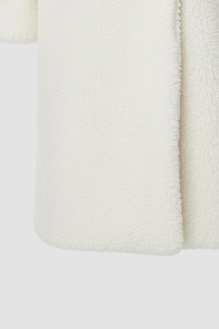 Close-up of a textured white fabric with a subtle pattern on a light gray background