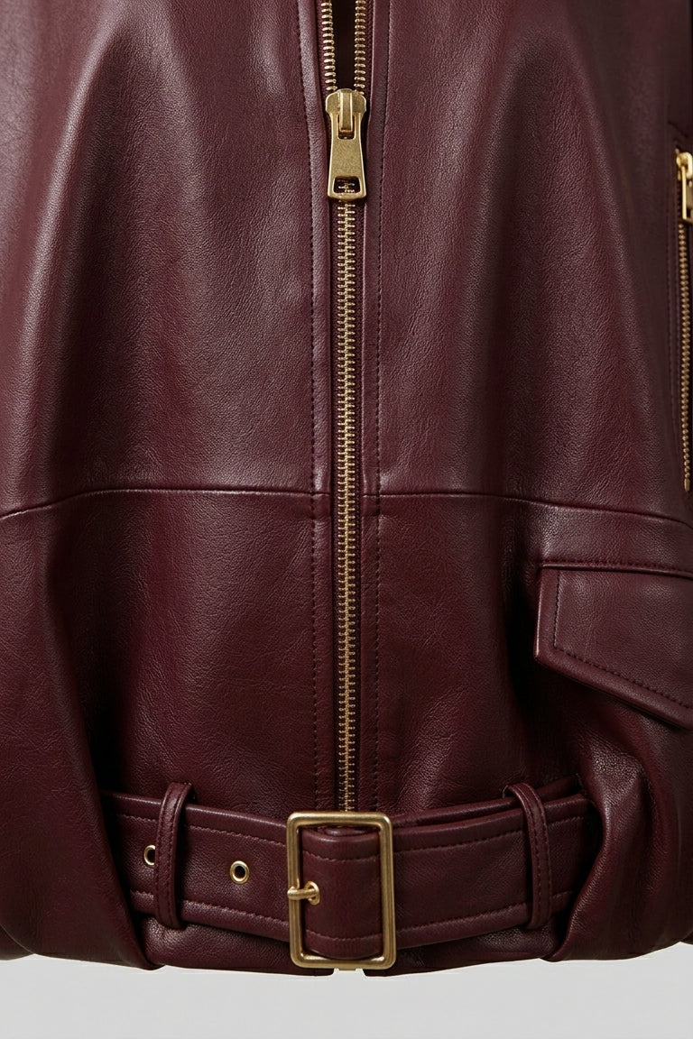 DELILAH - Close-up of burgundy leather jacket front zipper and belt detail