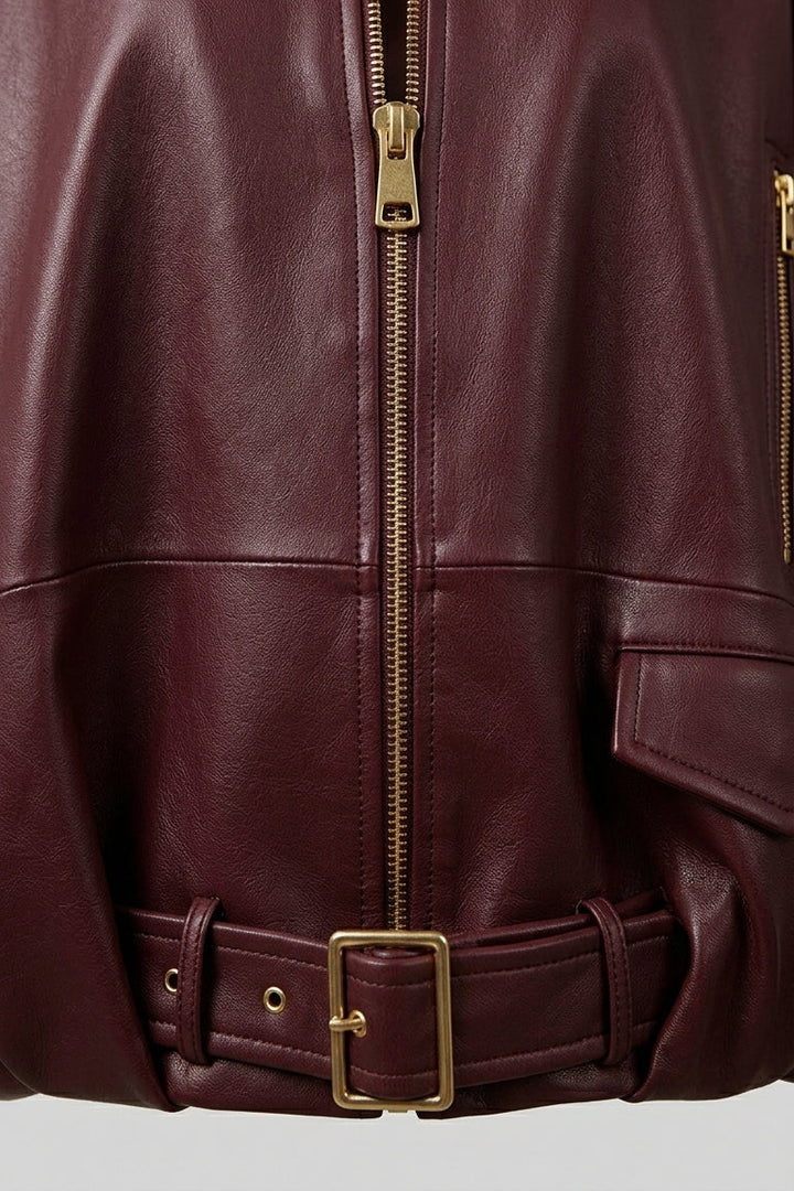 DELILAH - Close-up of burgundy leather jacket front zipper and belt detail