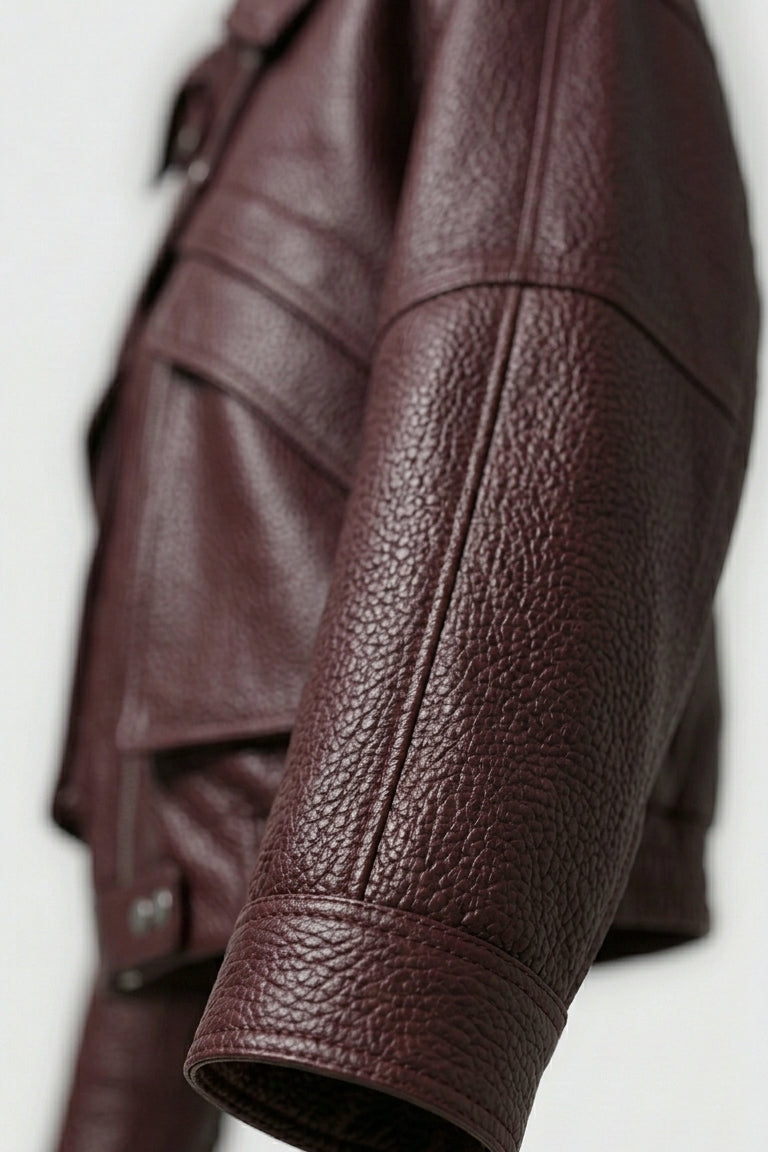 DREW - Close-up of a brown leather jacket sleeve on a white background