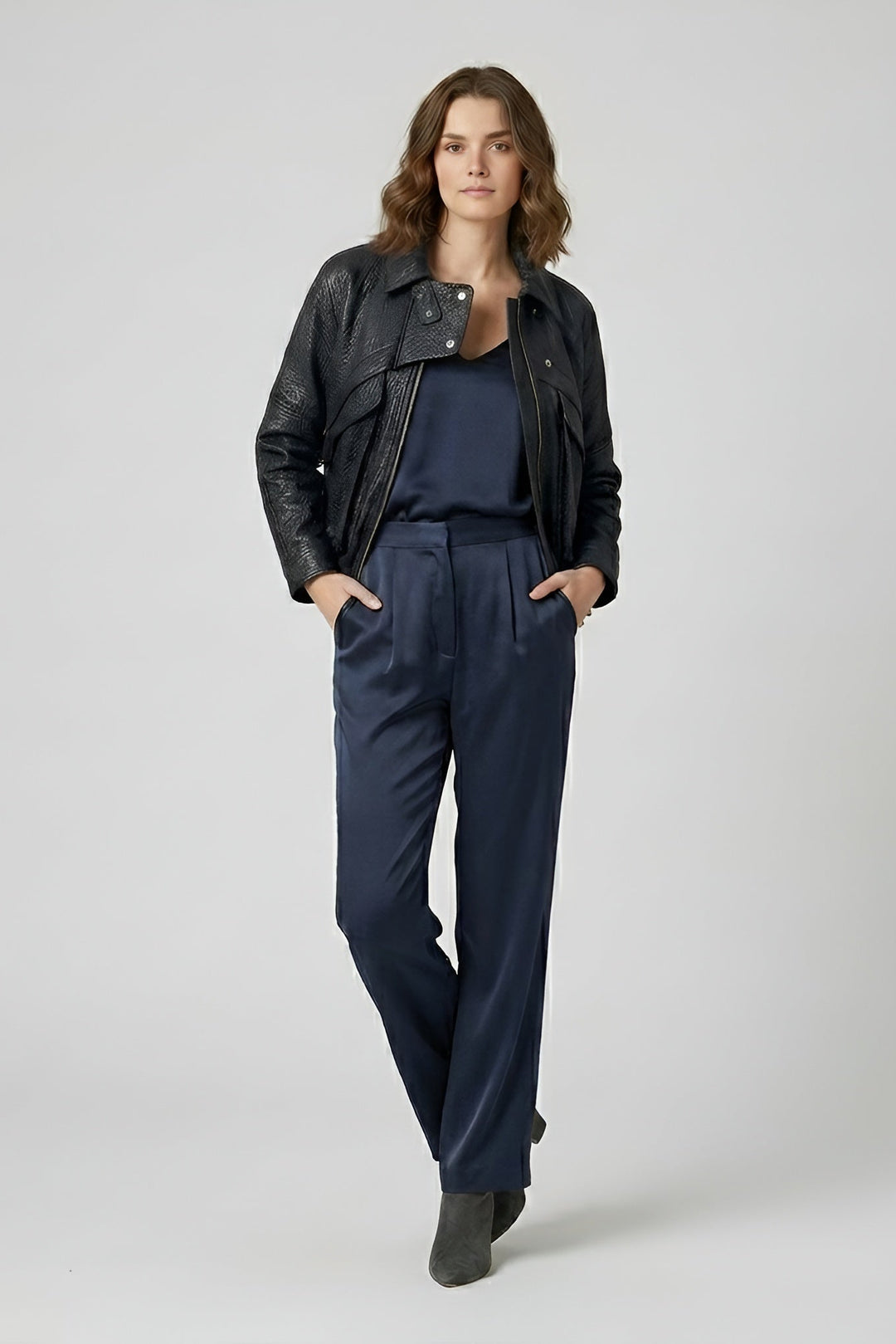 DREW - Woman wearing a black leather jacket and navy pants on a white background