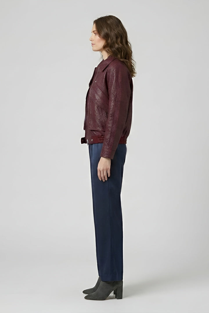 DREW - Woman wearing a maroon leather jacket and dark pants on a white background