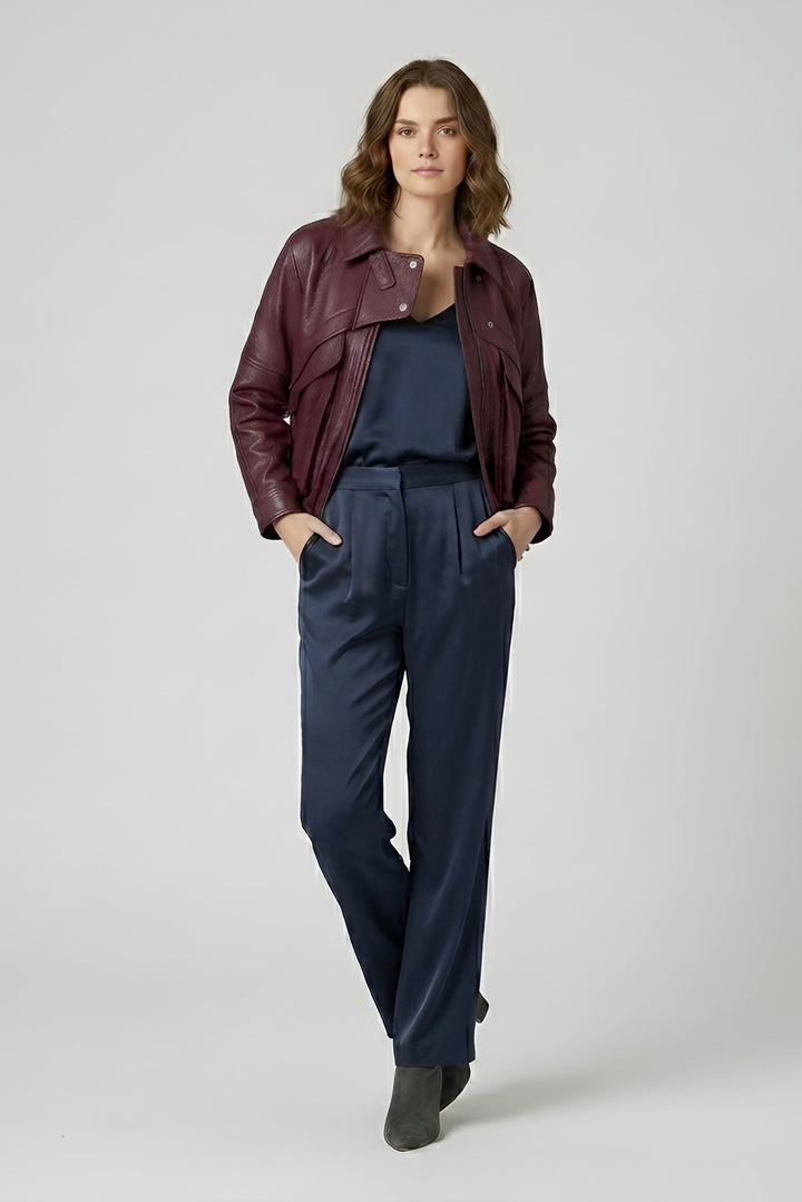 DREW - Woman wearing a maroon leather jacket and navy pants on a white background