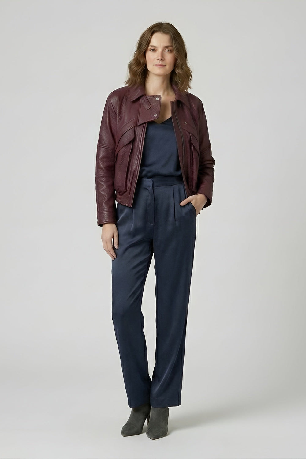 DREW - Woman wearing a maroon leather jacket and navy pants on a white background