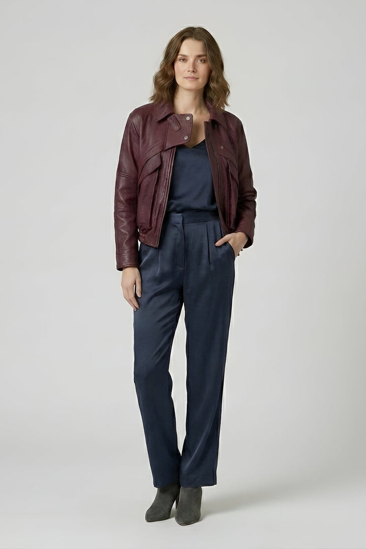 DREW - Woman wearing a maroon leather jacket and navy pants on a white background