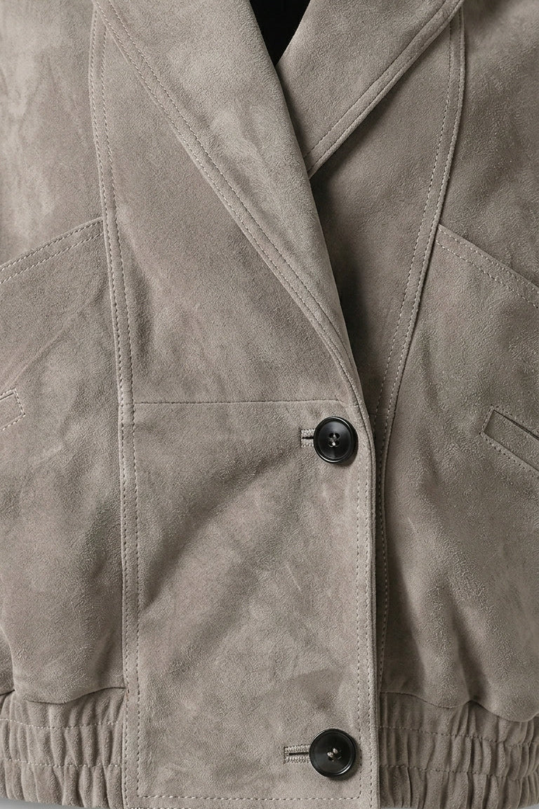 ELISE - Close-up of a beige suede jacket with black buttons on a white background