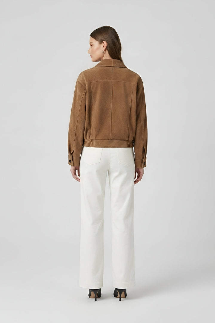 ELISE - Person wearing a brown jacket and white pants on a light gray background