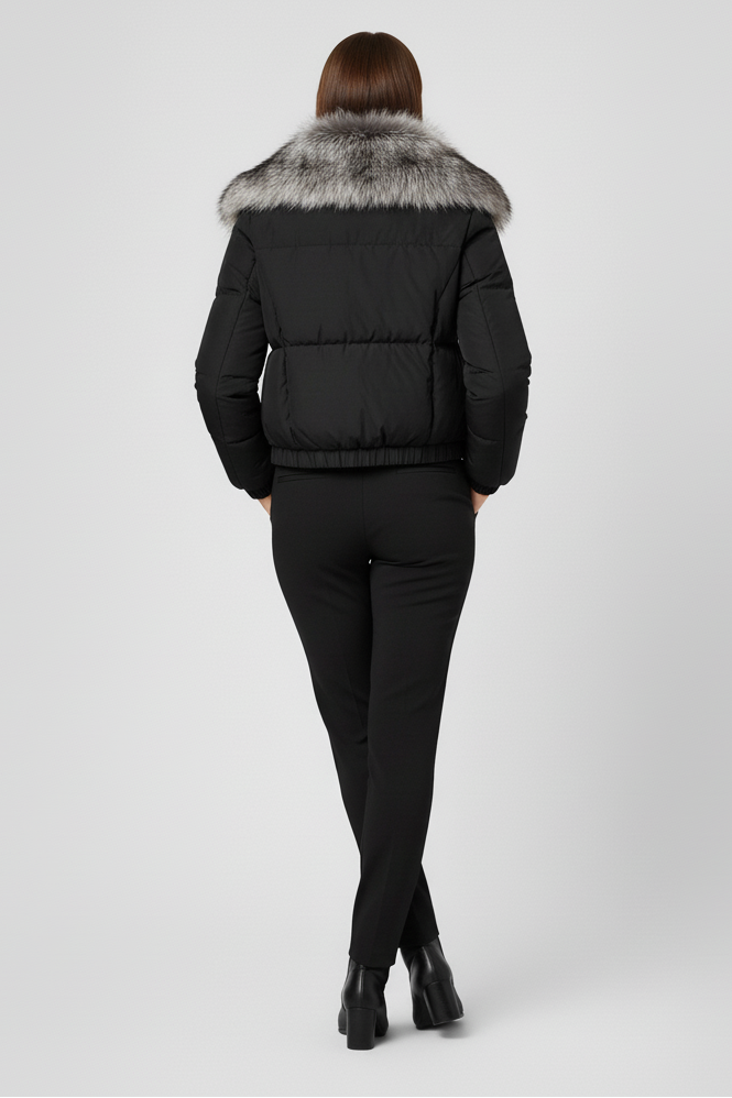 Person wearing a black puffer jacket with fur trim on a white background