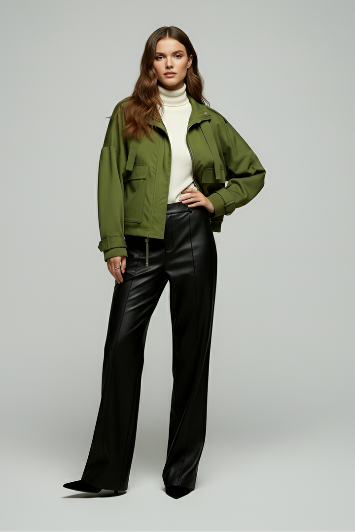 Woman wearing a green jacket and black pants on a gray background