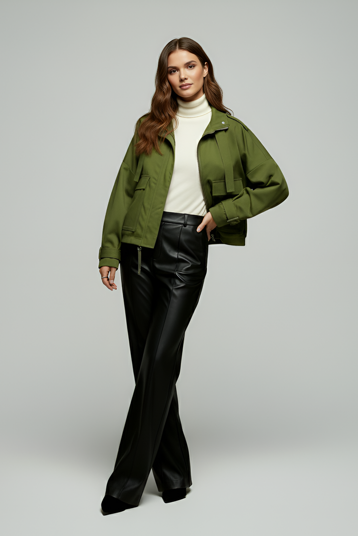 Woman wearing a green jacket and black pants on a gray background