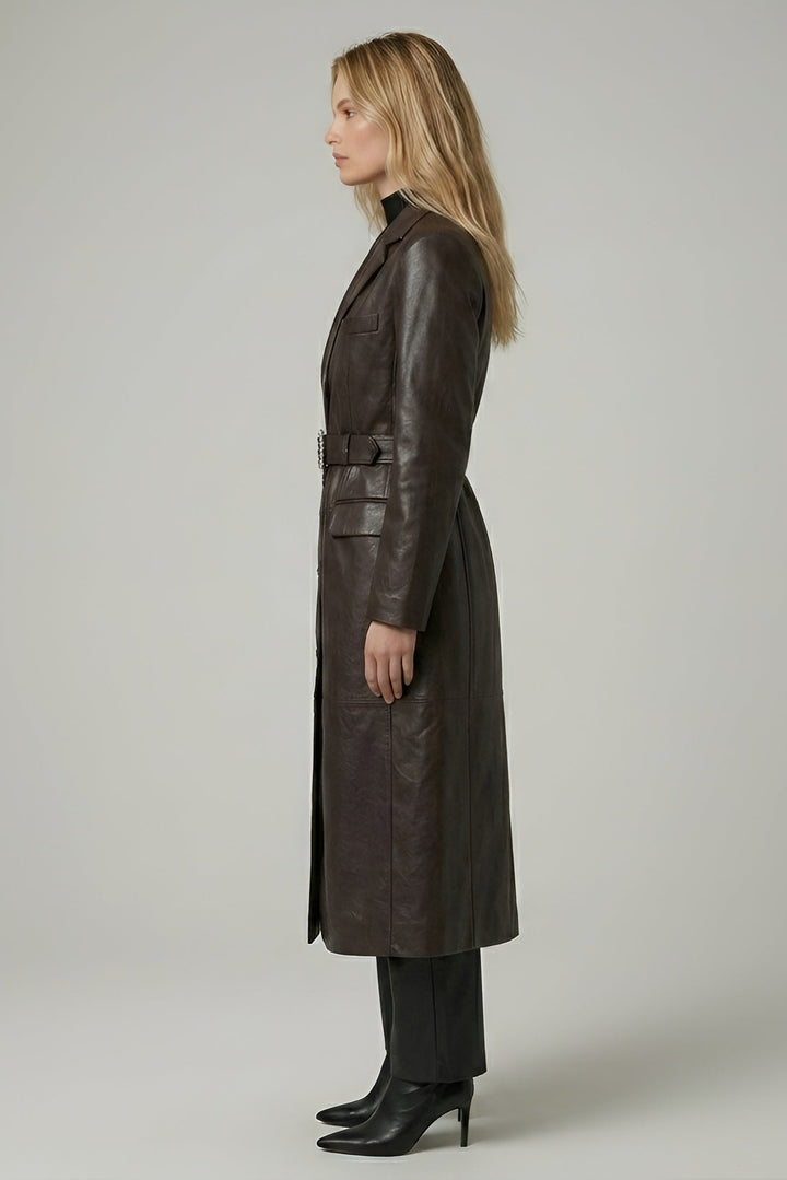 Woman wearing a long brown leather coat on a plain background