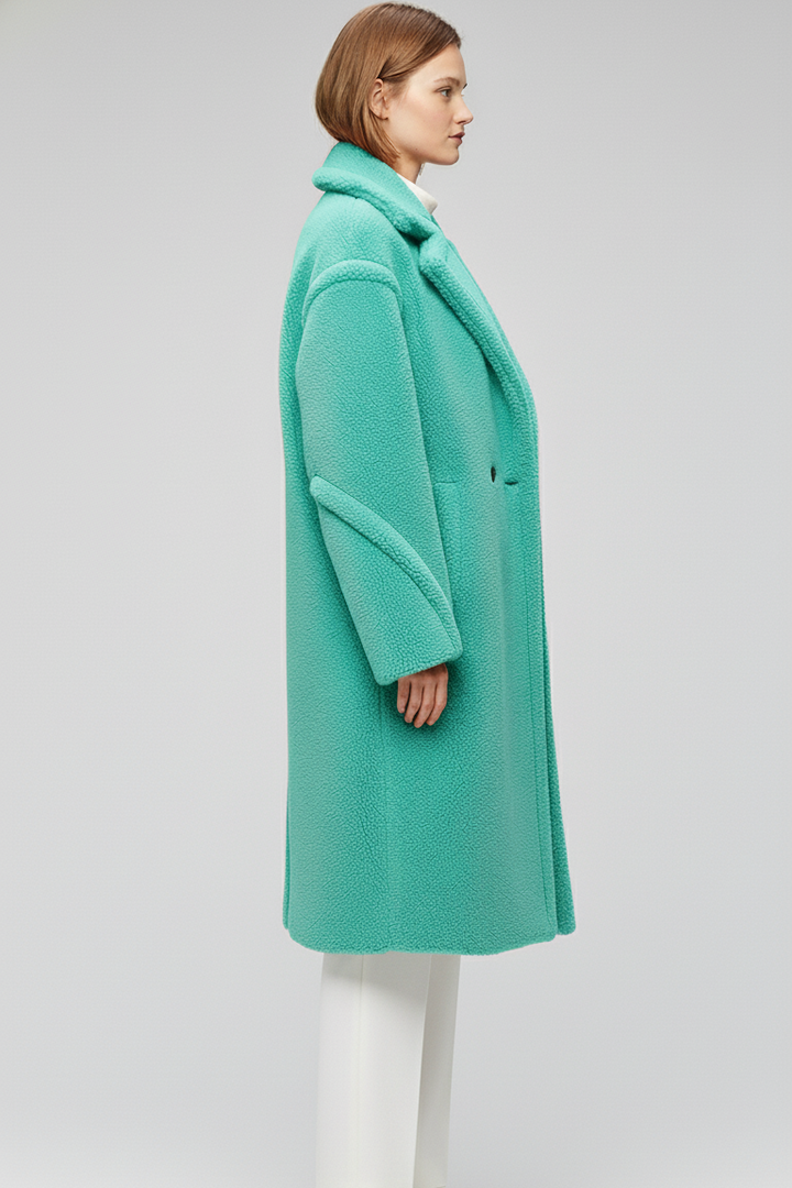Person wearing a teal coat on a plain background