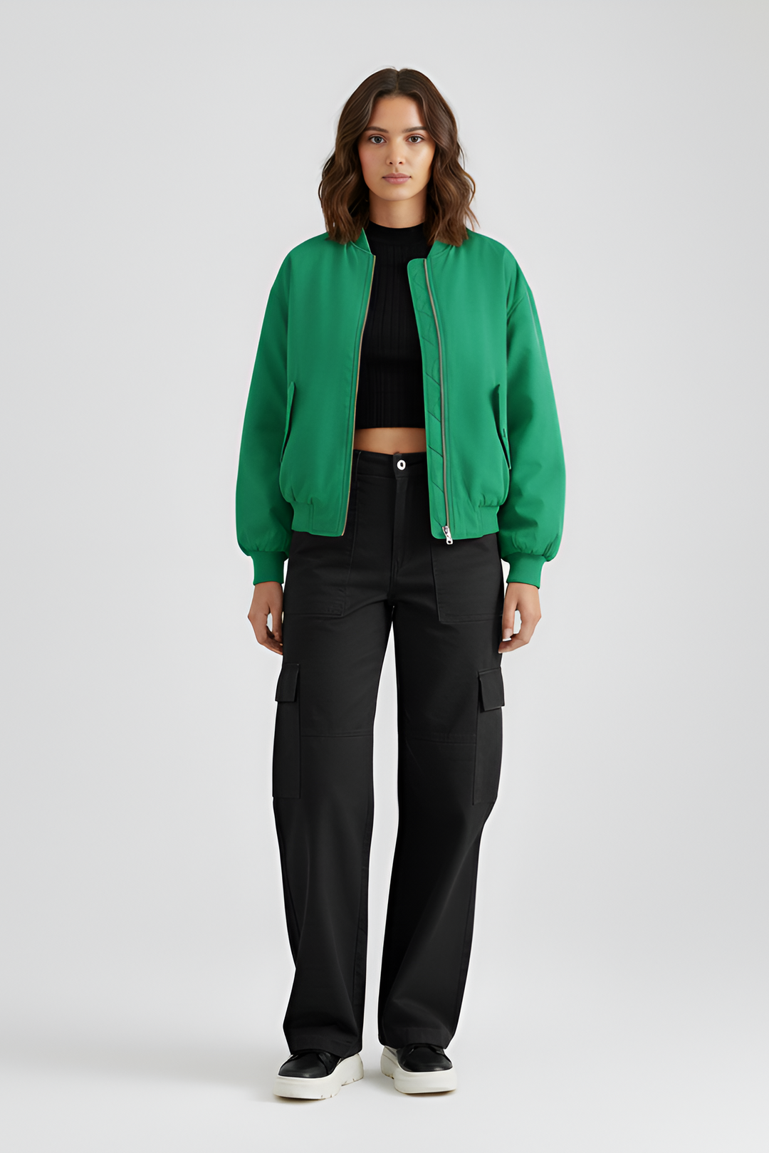 Person wearing a green jacket and black pants on a light gray background