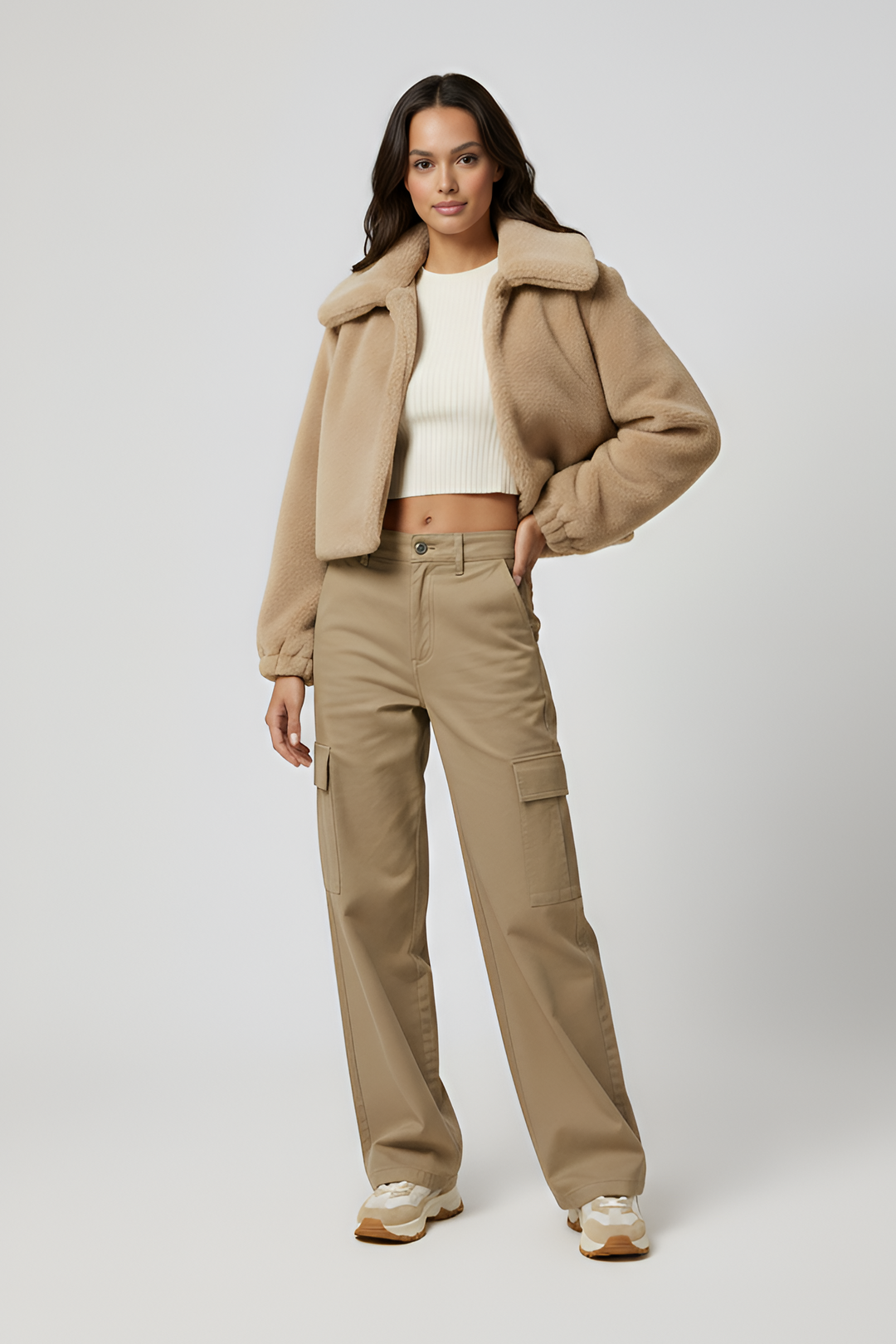 Person wearing a beige jacket and brown pants on a white background