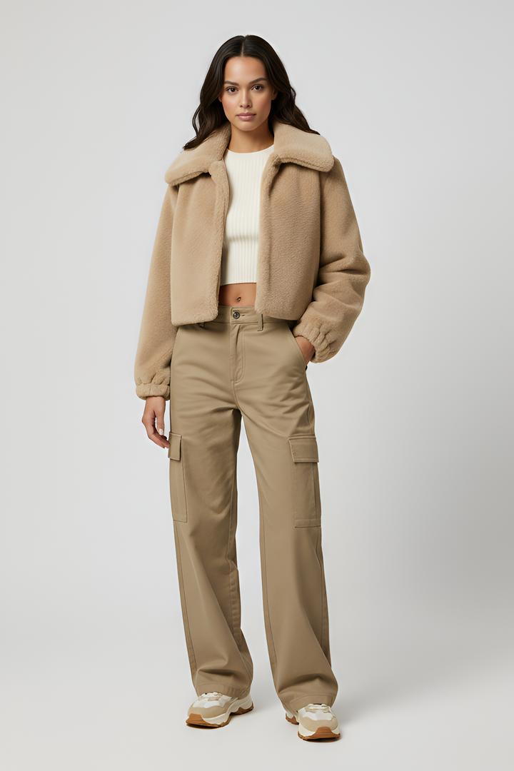 Person wearing a cream fur coat and dark pants on a light gray background