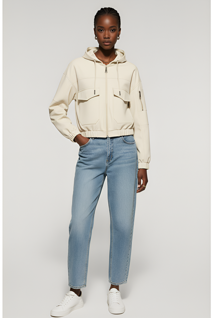 Person wearing a beige jacket and light blue jeans on a gray background