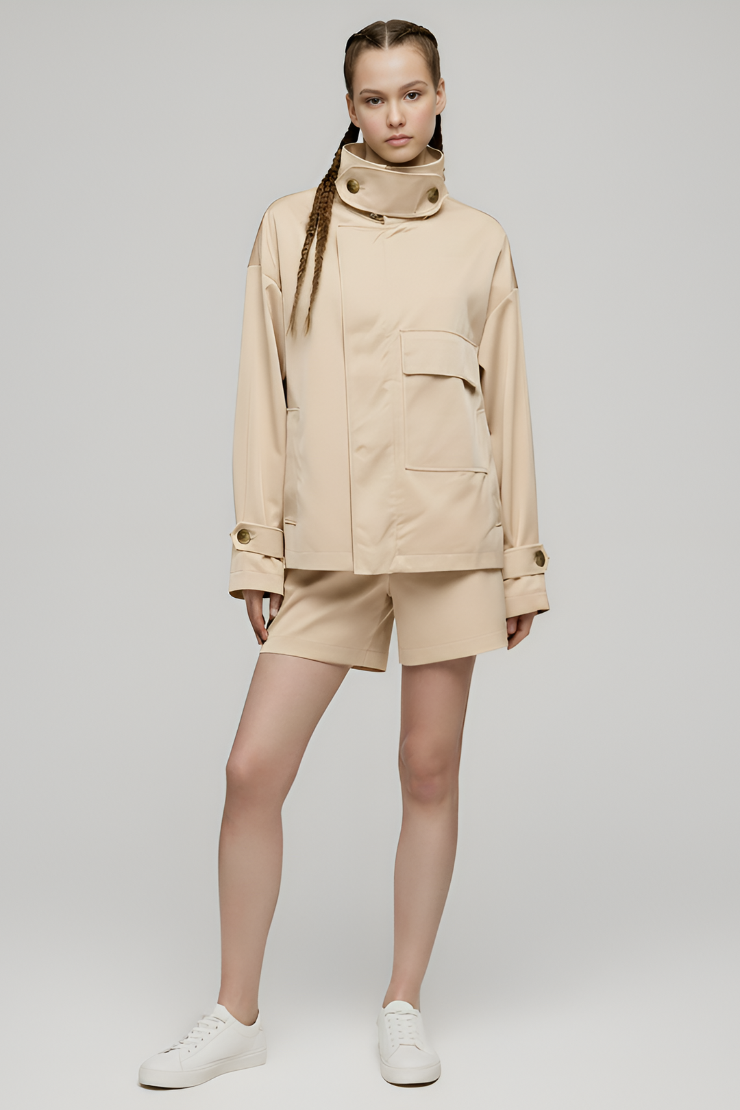Person wearing a beige jacket and shorts set on a plain background