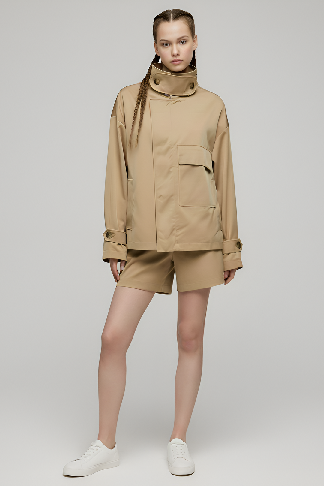 Person wearing a beige jacket and shorts set on a plain background