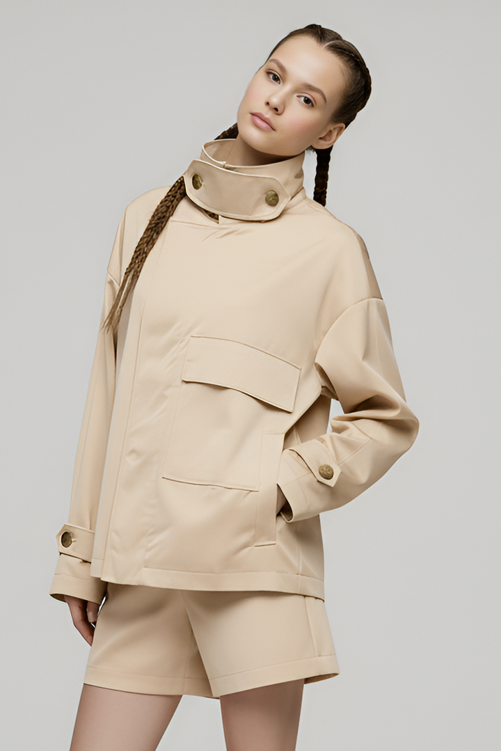 Person wearing a beige outfit with a jacket and shorts on a plain background