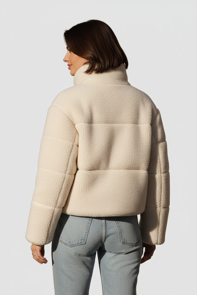 Person wearing a beige puffer jacket on a plain background