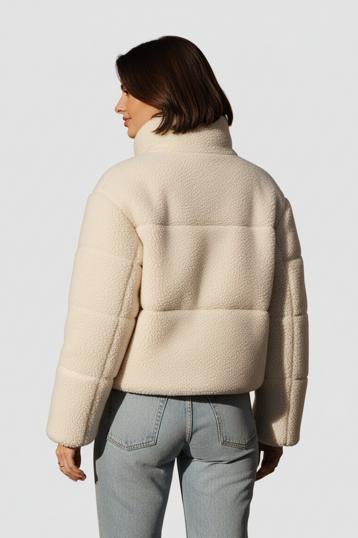 Person wearing a beige puffer jacket on a plain background