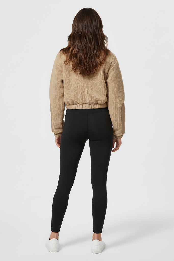 Person wearing a beige sweatshirt and black leggings on a white background