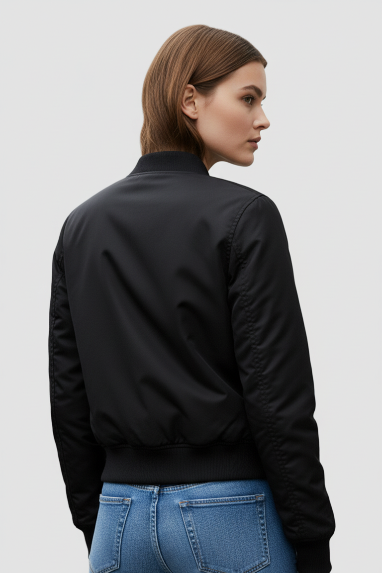 Person wearing a black bomber jacket and blue jeans on a light gray background