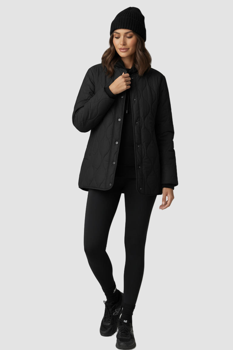 Person wearing a black coat, leggings, and beanie on a light gray background