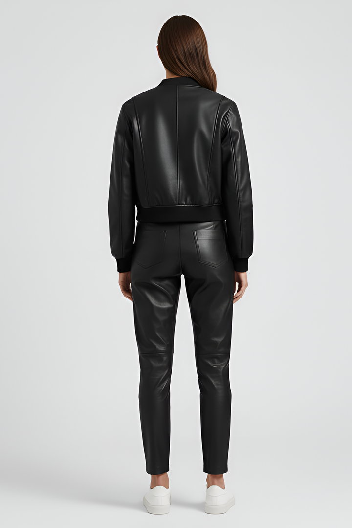 Person wearing a black leather bomber jacket and blue jeans on a white background