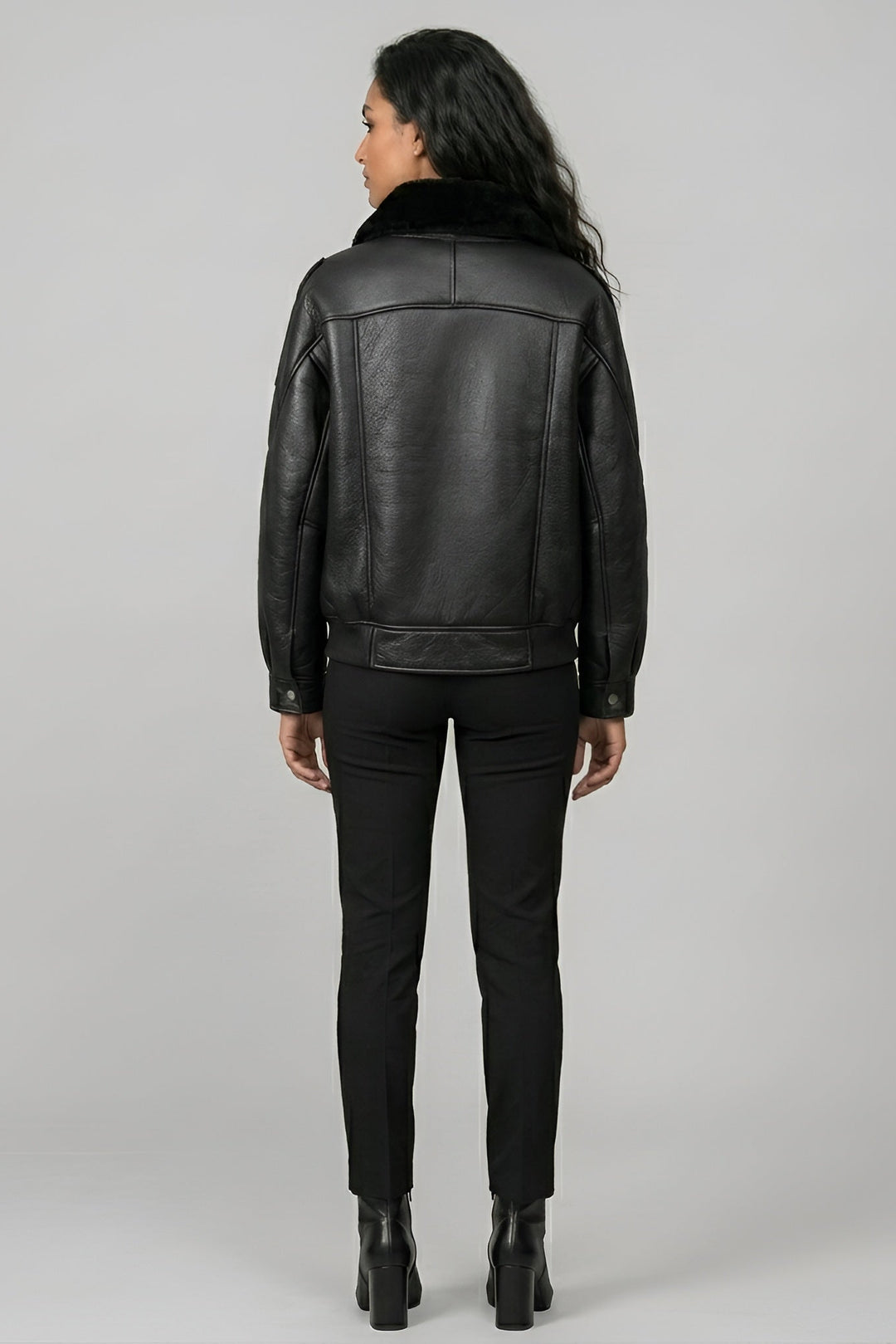 Person wearing a black leather jacket on a gray background